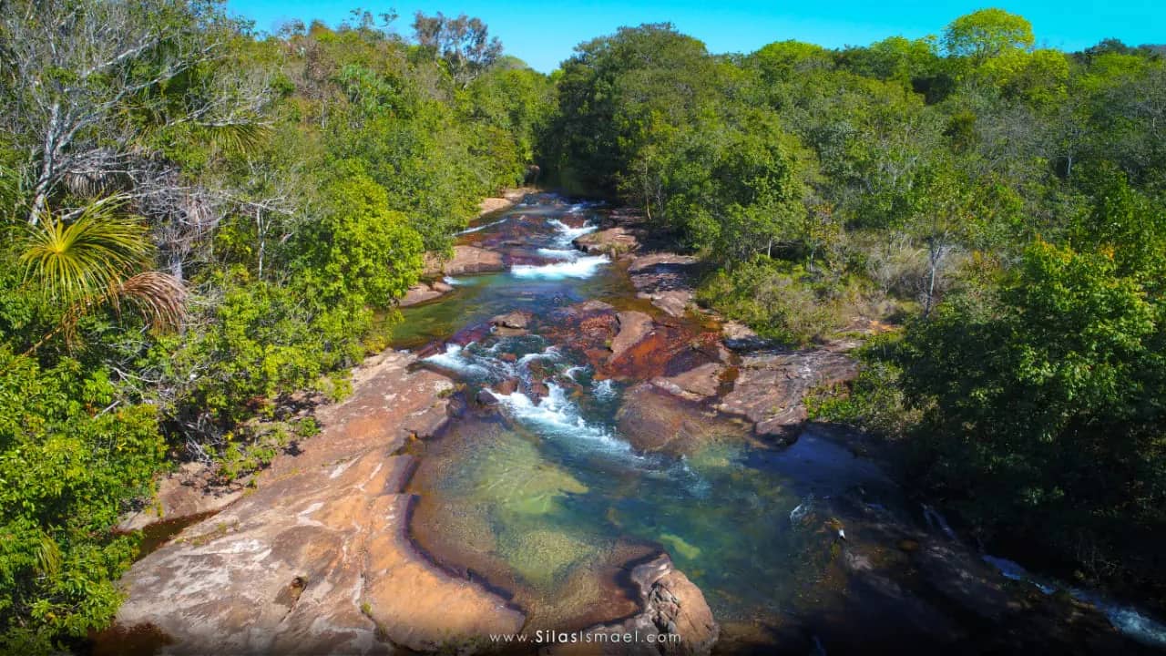 Vista do alto do rio de águas cristalinas correndo entre pedras e mata na Pousada Rancho da Princesa